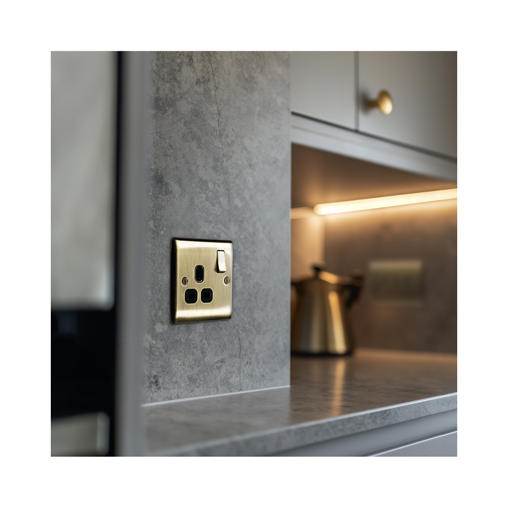 Brass electrical socket on a gray wall with a blurred kitchen background