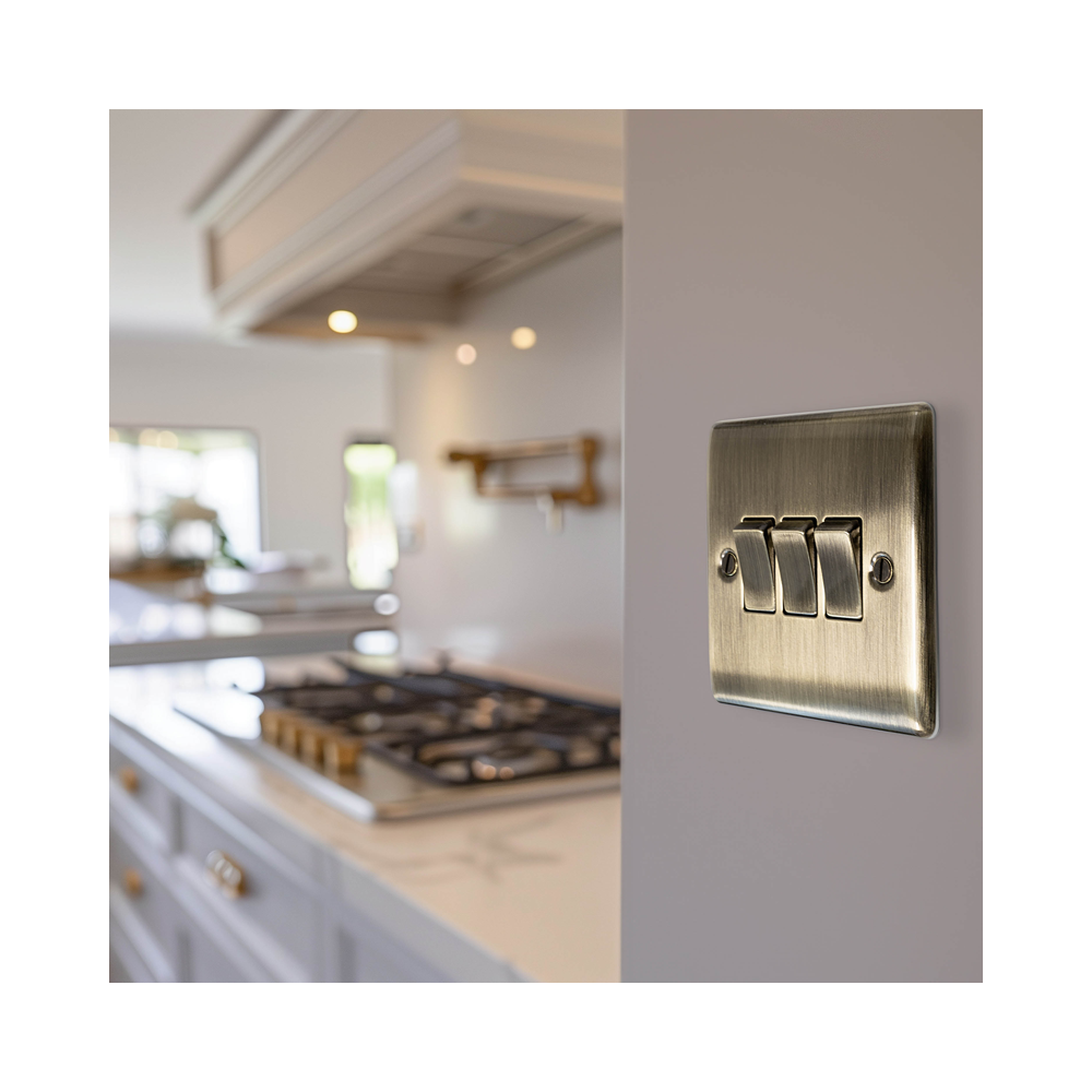 Metallic light switch on a kitchen wall with a blurred background of a kitchen.