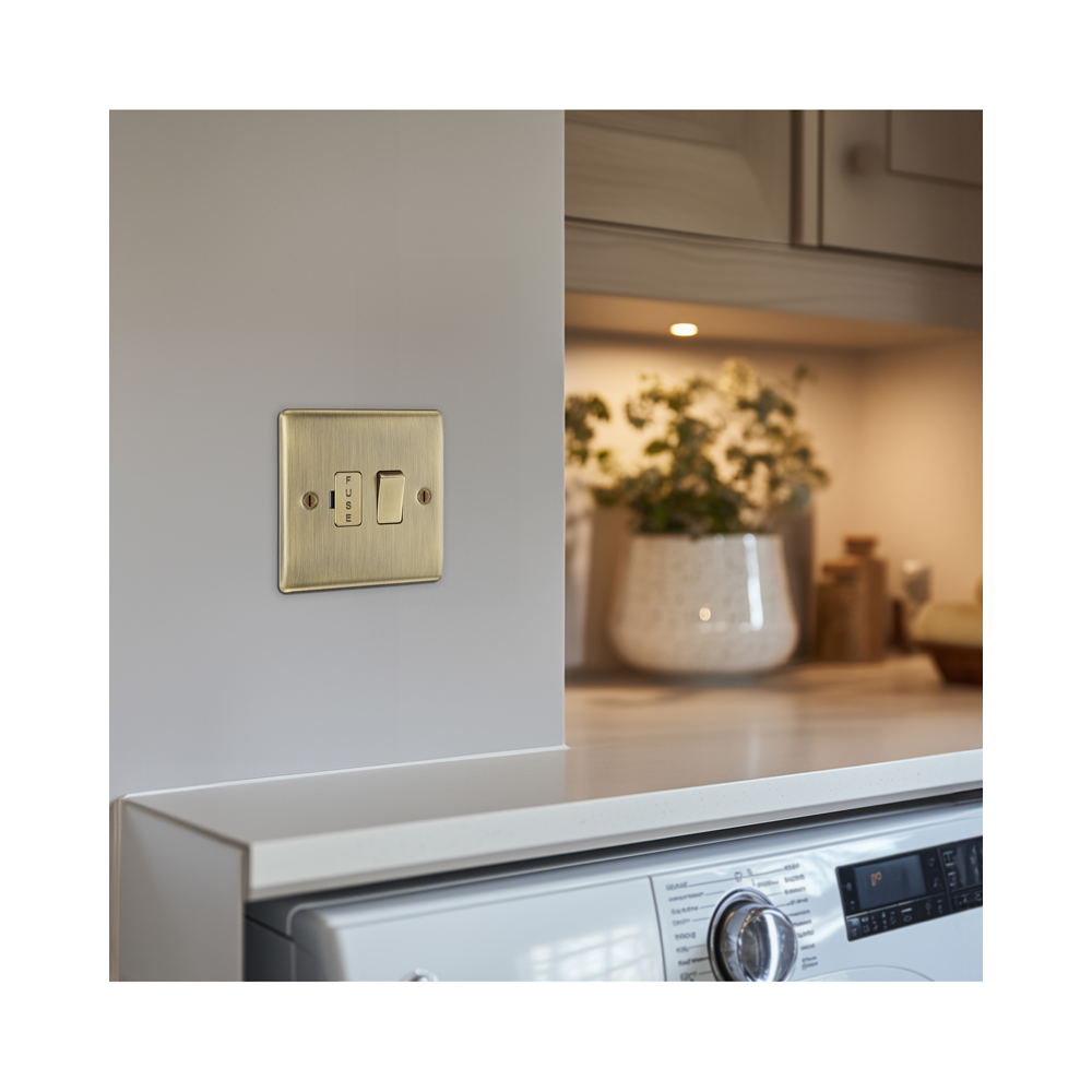 Brass fused light switch on a kitchen wall with a blurred background of a kitchen.