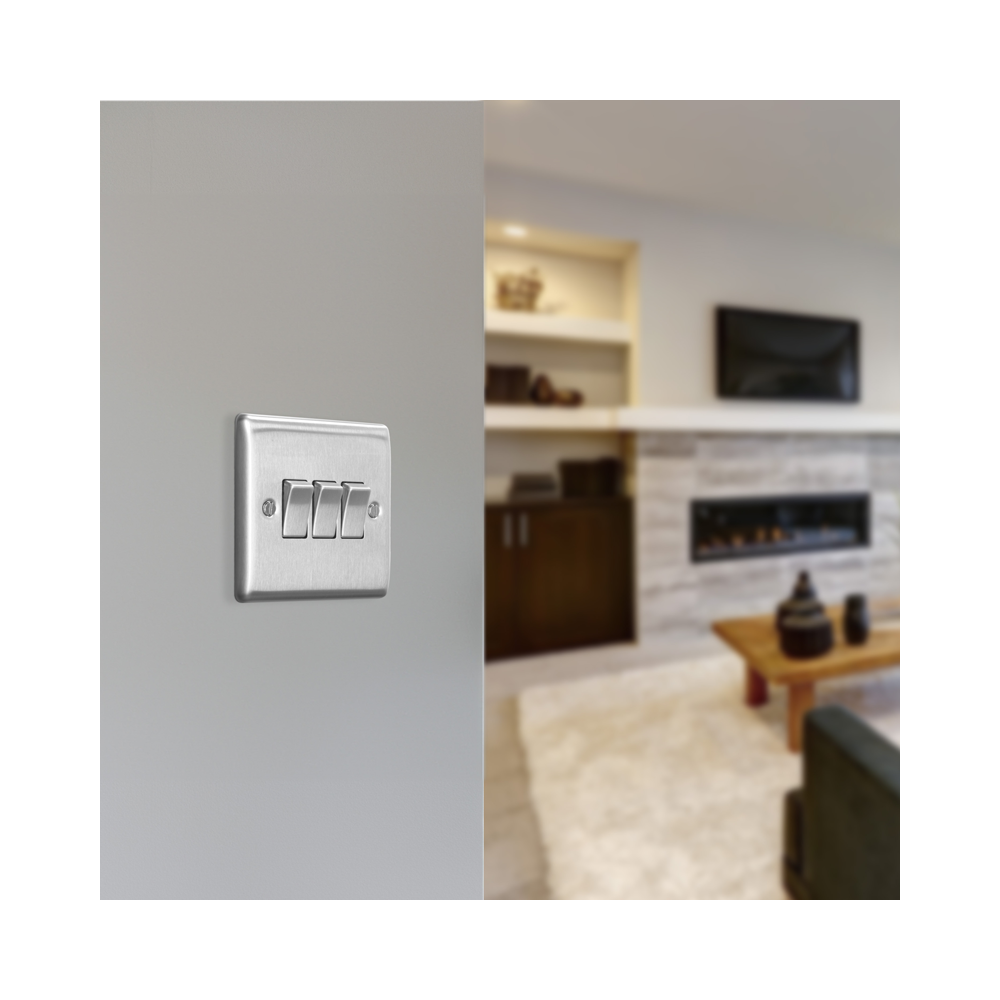 Metallic light switch panel with three toggle switches on a white background lounge setting