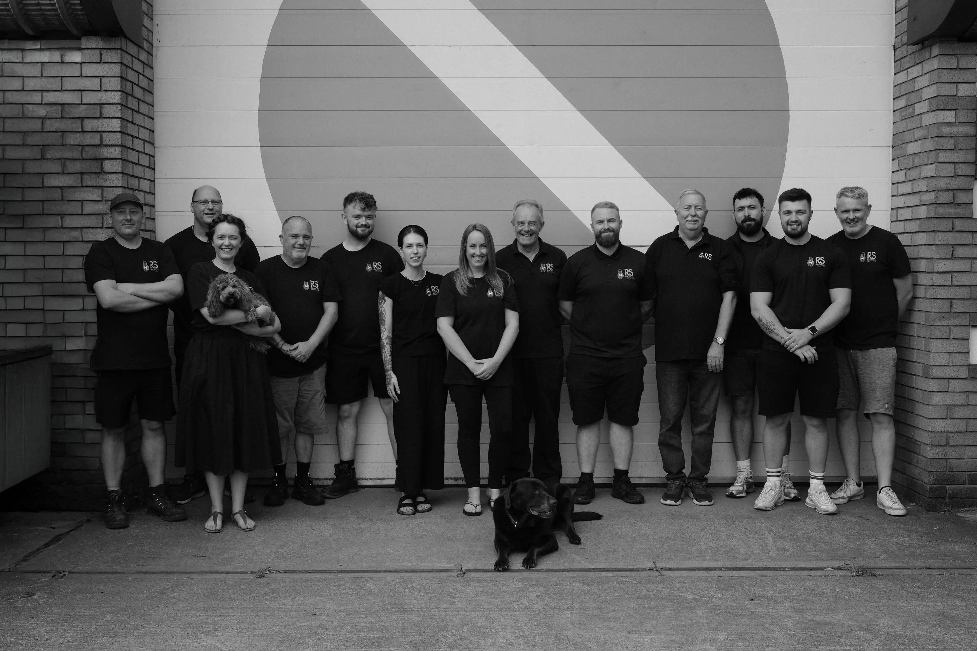 team photo showing men and woman in staff uniform with two dogs 